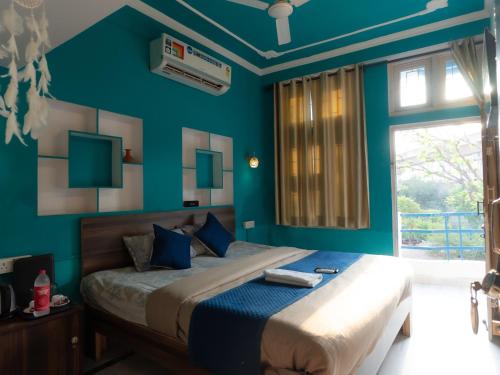 a bedroom with a bed with blue walls and a window at Flamingos Hostel Jaipur in Jaipur