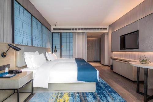 a hotel room with a large bed and a television at Echarm Hotel Torch Development Zone Zhongshan Station in Zhongshan