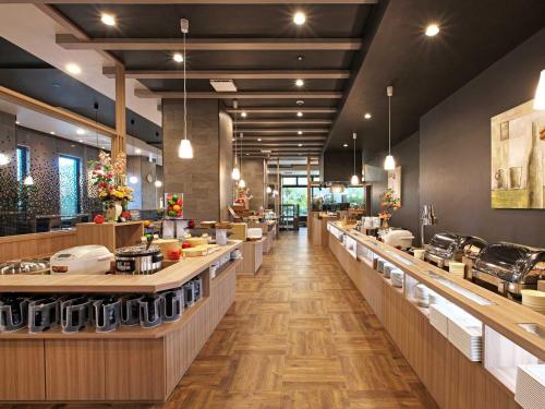 a restaurant with a long line of counters and tables at Hotel Route Inn Grand Misawa-EAST COURT in Misawa