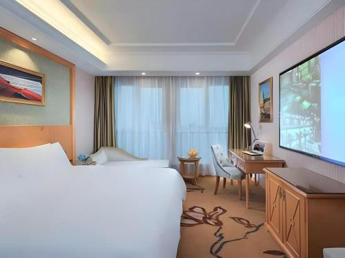 une chambre d'hôtel avec un grand lit et un bureau dans l'établissement Vienna Hotel Nanchang New Grand Hongcheng Market Xianghu 1st Hospital, à Nanchang