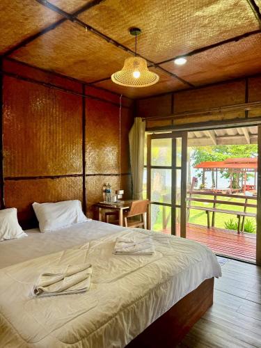 a bedroom with a large bed and a large window at Libong Beach Resort in Ko Libong