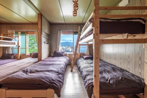 two bunk beds in a room with windows at TARUNE in Otaru