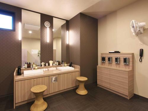三沢市にあるホテルルートインＧｒａｎｄ三沢－ＥＡＳＴ　ＣＯＵＲＴ－の洗面台が2つと大きな鏡があるバスルーム