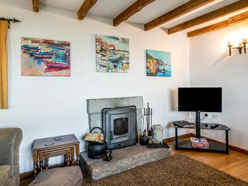 a living room with a fireplace and a tv at Wharrastone - Uk50661 in Crackington Haven