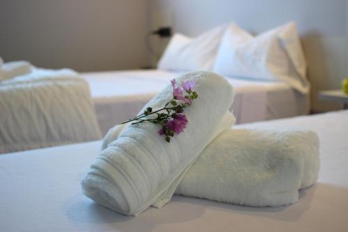un asciugamano arrotolato con un fiore su un letto di Pensión LO a O Pedrouzo