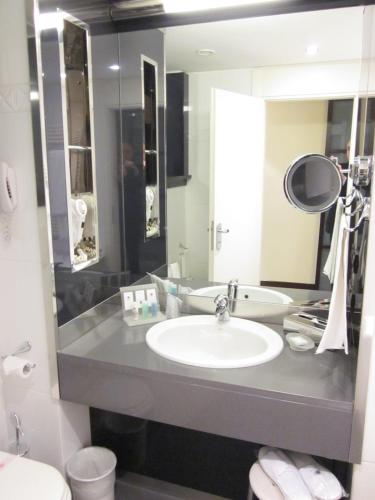 a bathroom with a sink and a toilet and a mirror at Grand Hotel De La Ville in Parma