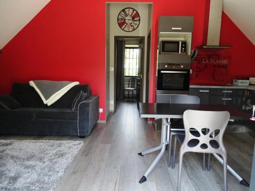 a living room with red walls and a table and chairs at Gîte La Planhe in Bozouls