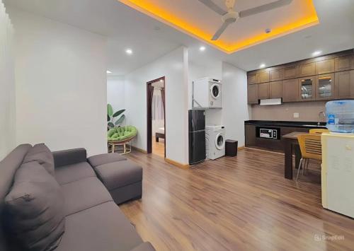Una sala de estar con un sofá y una cocina. en Moon Hotel Apt 3 Pham Tuan Tai, en Hanói