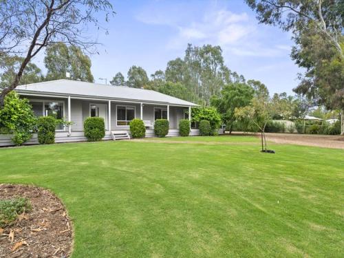 a white house with a green lawn in front of it at River Retreat in Yarrawonga