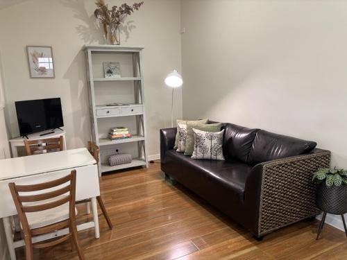 a living room with a black leather couch and a table at 1839 Cottages in Willunga