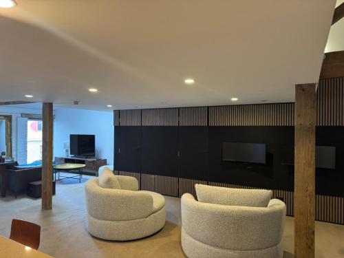 a living room with two chairs and a television at Boxwood IXL Luxe Hobart Waterfront Apartment in Hobart