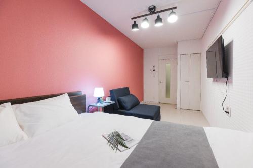 a bedroom with a bed and a chair and a television at VILLA SAKURA Hatanodai II in Tokyo
