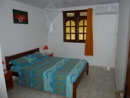 a bedroom with a bed and a window at Appartements Allée des Ixoras in Saint Esprit