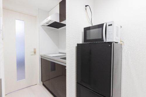 a microwave on top of a refrigerator in a kitchen at VILLA SAKURA Hatanodai II in Tokyo