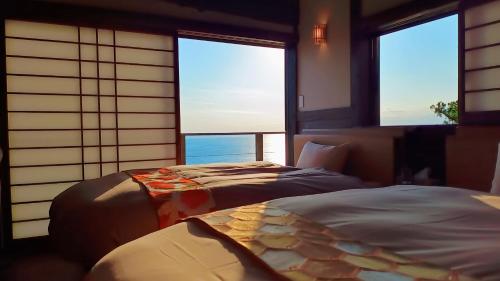 two beds in a room with two windows at Elysian view izu in Koura