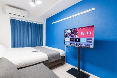 a bedroom with a bed and a tv in a blue wall at VILLA SAKURA Hatanodai II in Tokyo