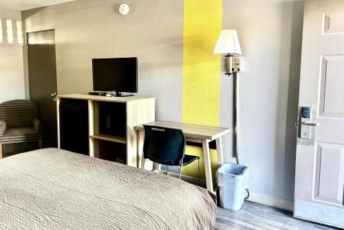 a bedroom with a bed and a desk with a television at Super 8 by Wyndham Albuquerque Downtown in Albuquerque