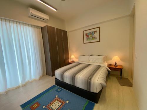 バトゥ・フェリンギにあるBy The Sea Luxury Beachfront Resort 223のベッドルーム1室(ベッド1台、テーブルにランプ2つ付)