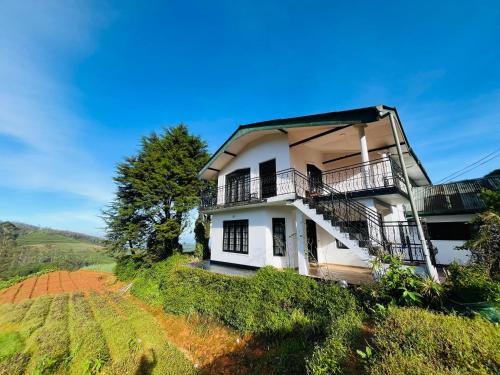a white house with balconies on a hill at The Crowns Lodge in Nuwara Eliya