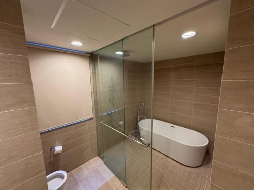 a bathroom with a glass shower with a tub and a sink at BY THE SEA - Penthouse 3 bedroom in Batu Ferringhi