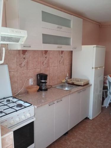 a kitchen with white cabinets and a sink and a stove at Casa Sahar in Turda