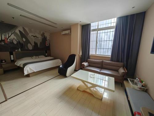 a bedroom with a bed and a couch and a table at Thank Inn Hotel He'nan Xinxiang Changyuan Bo'ai Road in Changyuan
