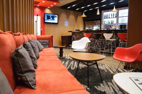 an orange couch in a bar with chairs and a table at ibis Sao Paulo Paulista in Sao Paulo