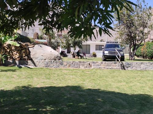 a truck parked in a yard with a rock wall at La Casita de Condoray - Lunahuana in Lunahuaná