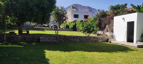 a yard with a white house and a building at La Casita de Condoray - Lunahuana in Lunahuaná