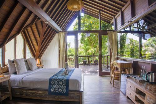 Un dormitorio con una cama en una habitación con ventanas. en Green Tree House Villa Ubud, en Ubud