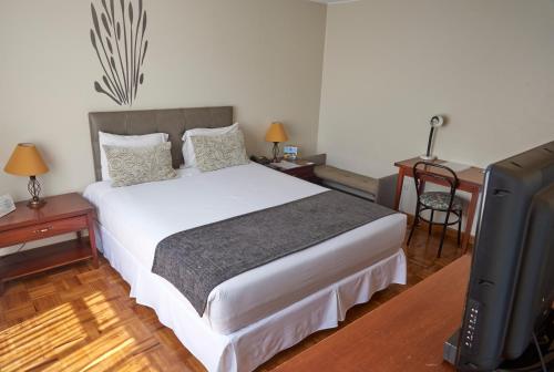 um quarto com uma cama e uma televisão de ecrã plano em Embassy Quito em Quito