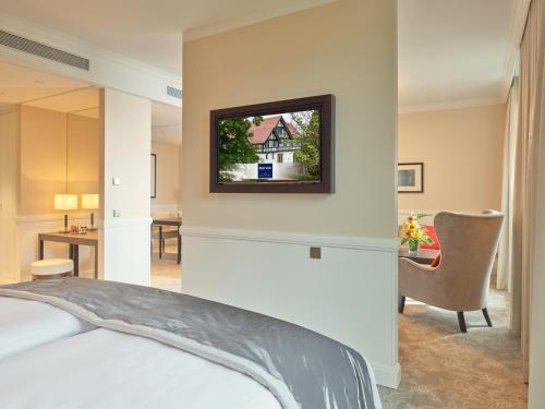 a bedroom with a bed and a tv on the wall at Dorint Hotel Frankfurt/Oberursel in Oberursel