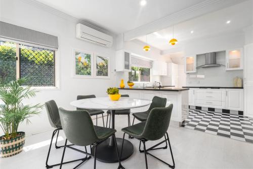 una cucina bianca con tavolo e sedie di Bird and Leaf Cottage a Brisbane