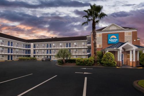 a hotel with a palm tree in a parking lot at Suburban Studios Stuart near Federal Hwy 1 in Stuart