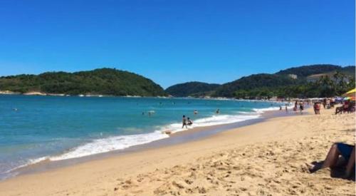 a beach with a lot of people in the water at Vila jequitimar in Guarujá