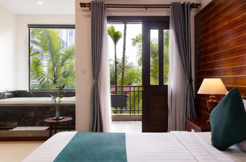 a bedroom with a bed and a balcony with a tub at Green Amazon Residence in Siem Reap