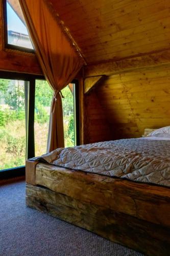 a bed in a wooden room with a large window at Old Chalet in Iaşi