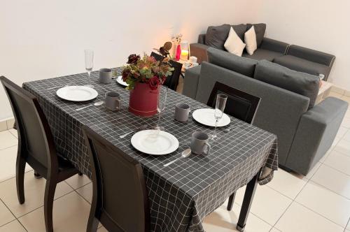 a table with plates and wine glasses and a couch at J Cozy Stay - 3B 2B, Fair Park Ipoh in Ipoh