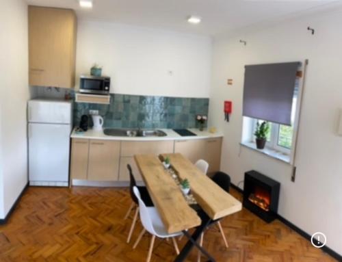 a kitchen with a table and chairs and a fireplace at Alojamento D. Duarte in São Paio