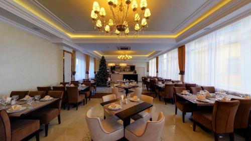 a restaurant with tables and chairs and a chandelier at Argo Premium in Lviv