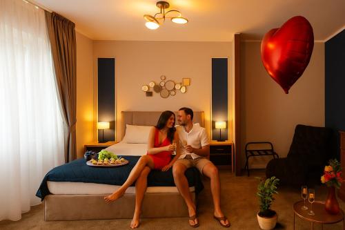 a man and a woman sitting on a bed at Al Centro in Bucharest