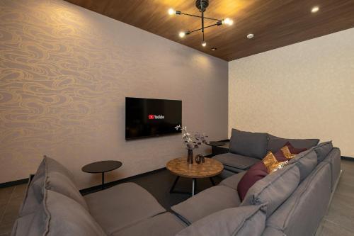 a living room with a couch and a tv on a wall at JAPAVISTA Leggero in Osaka
