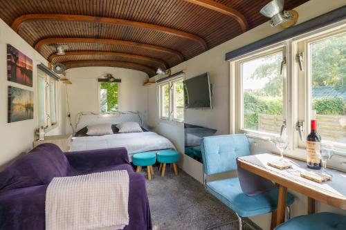 a room with a bed and a table and chairs at Gezellige Pipo met grote schommel aan het water en hottub in Medemblik