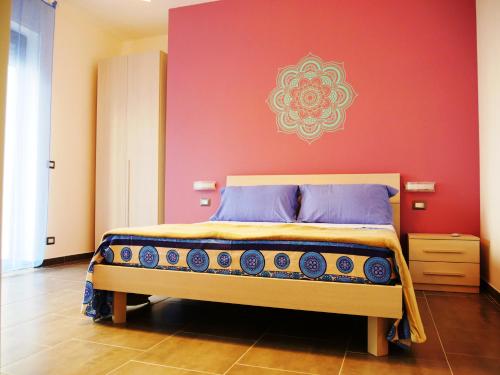 um quarto com uma cama com uma parede vermelha em Casa Namasté em Lecce