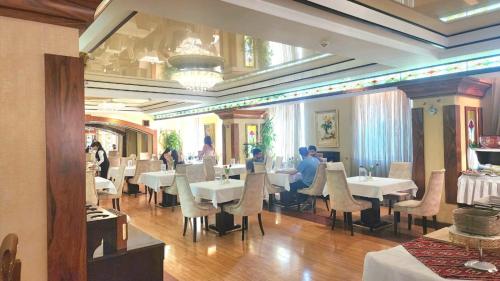 a restaurant with tables and chairs and people sitting at them at Genceli Family Hotel in Baku