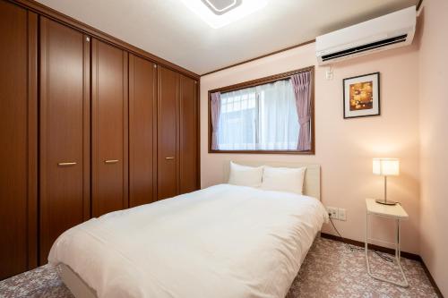 a bedroom with a large white bed and a window at Familia Kamata 1 in Tokyo