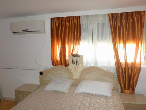 1 dormitorio con 1 cama con 2 almohadas y ventana en Aldom Apartments, en Durrës