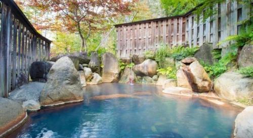 a pool of water with rocks and a fence at Hirayu Prince Hotel in Takayama