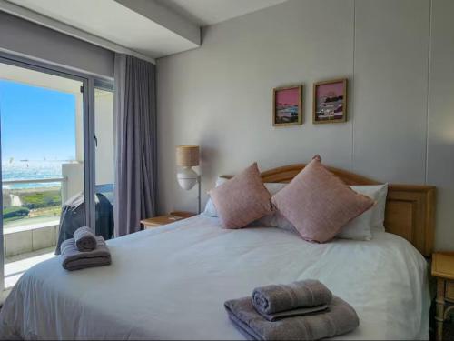 une chambre avec un grand lit avec une grande fenêtre dans l'établissement Dolphin Delight, à Bloubergstrand