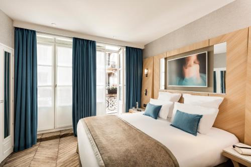 une chambre d'hôtel avec un grand lit blanc avec des oreillers bleus dans l'établissement Hotel Louvre Saint-Honoré, à Paris